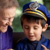 A young boy wearing a policeman costume, sitting with his grandmother.
