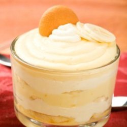 Cup of banana pudding topped with whipped cream and a vanilla wafer cookie.