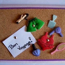 Finished Bon Voyage Card with foam swimsuits, brush, curling iron attached to cork board with brads.