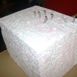 Block of Styrofoam with nails and screws pushed partway into it