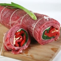 Rolled flank steak stuffed with spinach, peppers, and cheese, ready for cooking.