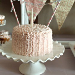 small pink cake with one candle and bunting strung across