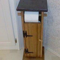 A bathroom toilet paper holder that is built like an outhouse.