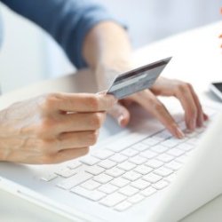 A woman typing in a credit card number for an online shopping purchase.