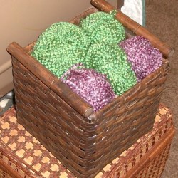 Finished basket storage, with balls of green and purple yarn artfully arranged on top.