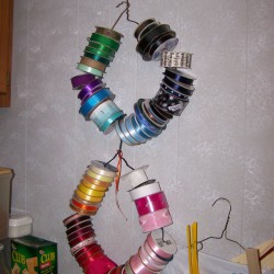 Rolls of ribbon on two wire hangers hanging on the wall.