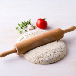 Rollong pin on round of pizza dough.