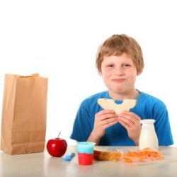 A child eating a brown bag lunch.