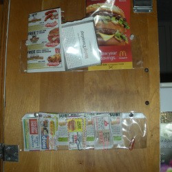 Organized restaurant coupons taped inside cabinet door 