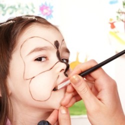 A girl at a harvest festival having her face painted.