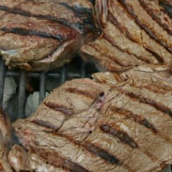 Several steaks on the grill.