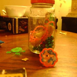 Side view of jar with toys inside and next to it on table.