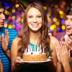 A 16 year old girl holding a cake at her birthday with friends.