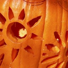 A flower or sun pattern carved into a pumpkin.