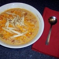 A bowl of Chicken Tortilla Soup next to a napkin and spoon.