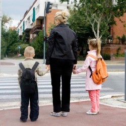 A mom and two kids crossing the street.