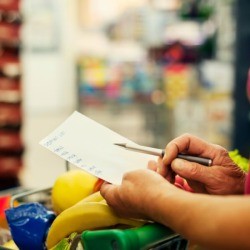 A woman looking at her shopping list in a supermarket.
