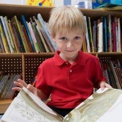 A young boy reading a large book.