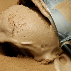 Getting a scoop of chocolate ice cream from the container.