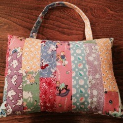 patchwork child's pillow with vertical one inch stripes of various 1930s reproduction fabric