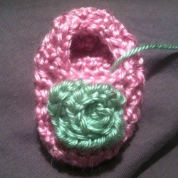 A crocheted rosebud on a baby bootie. 