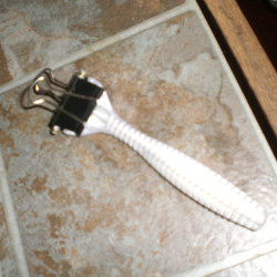 A binder clip over the blade portion of a disposable razor.