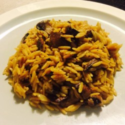 A plate of orzo risotto with mushrooms and cheese. 