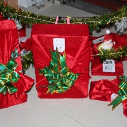 Fabric Wrapping Paper - variety of gifts wrapped in red stretch velvet with green bows 