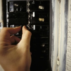 human hand flipping the switch on the circuit breaker.