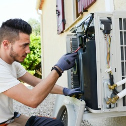 Man repairing an exterior home air conditioning unit