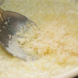 Adding Parmesan cheese to a pot of risotto.