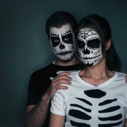 Couple in t-shirts ripped to look like a skeleton and sugar skull facepaint