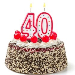 Burning candles shaped like the number 40 on a cake against a white background