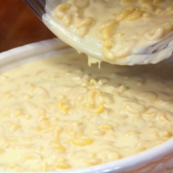Macaroni and cheese being poured from a saucepan to a serving dish