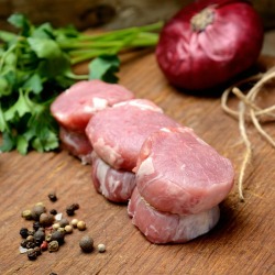 Raw pork medallions surrounded by fresh seasoning ingredients
