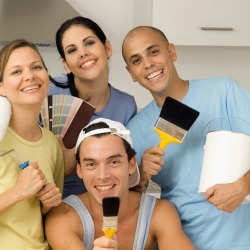 Group of people holding painting supplies and samples in a white kitchen