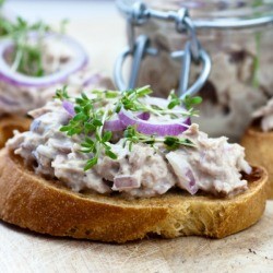 Creamed tuna on slices of toast garnished with herbs and red onion