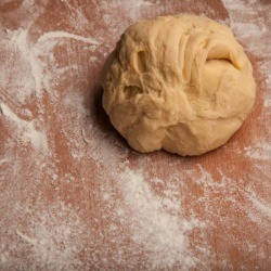 Ball of pizza dough on flour dusted work surface