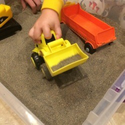 Indoor Sandbox - child's hand playing with bulldozer