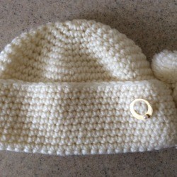 white knit hat with circle pin on folded up bottom 