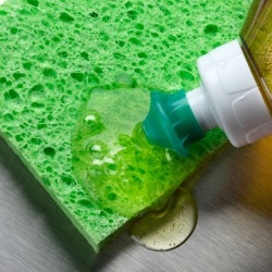 Dishwashing liquid being squeezed onto a sponge.