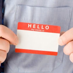 A man adhering a sticky name badge label to his dress shirt.