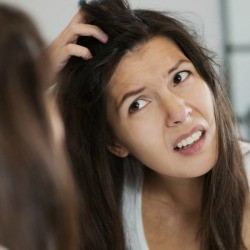 A woman noticing dandruff in her dark hair.
