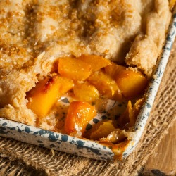 A pan of peach cobbler with a serving removed.