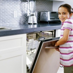 A girl opening a dishwasher at home.