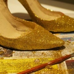 A pair of shoes that have been painted with gold glitter. 