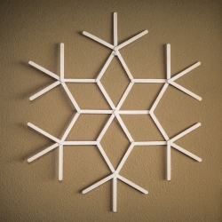 A finished popsicle stick snowflake, painted white.