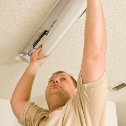 A man fixing a fluorescent light.