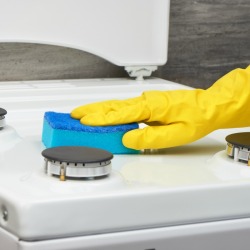 Hand wiping stove with a sponge.