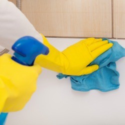 Person wearing rubber gloves cleaning a bathtub.